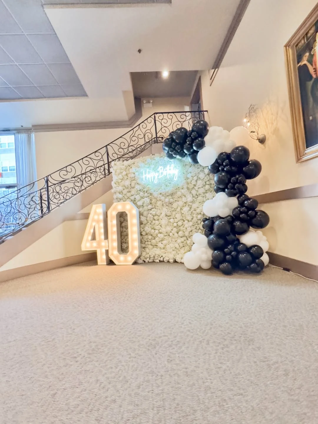 White flower wall with black and white balloons and illuminated 40 marquee numbers