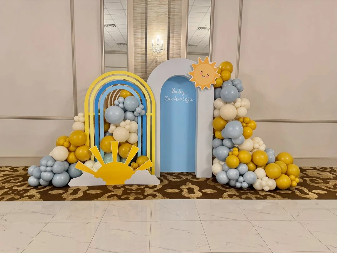 Blue and yellow sunshine balloon installation with a rainbow backdrop