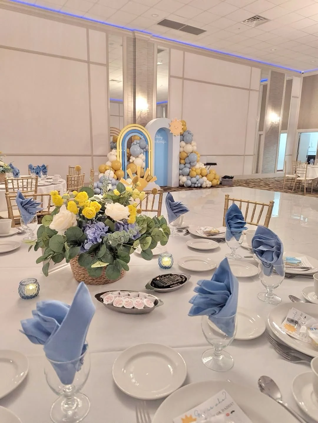 Sunshine themed baby shower with blue and yellow balloons and styled tables
