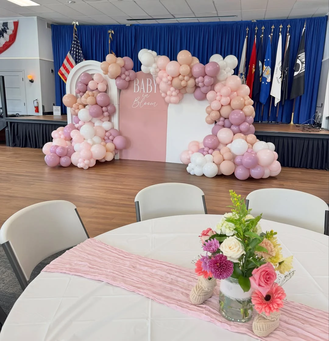 Pink Baby in Bloom balloon backdrop with a floral centerpiece in the foreground